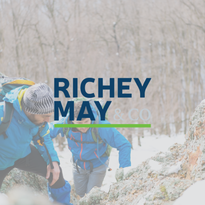 Richey May & Co title with background of two men reading a map outside