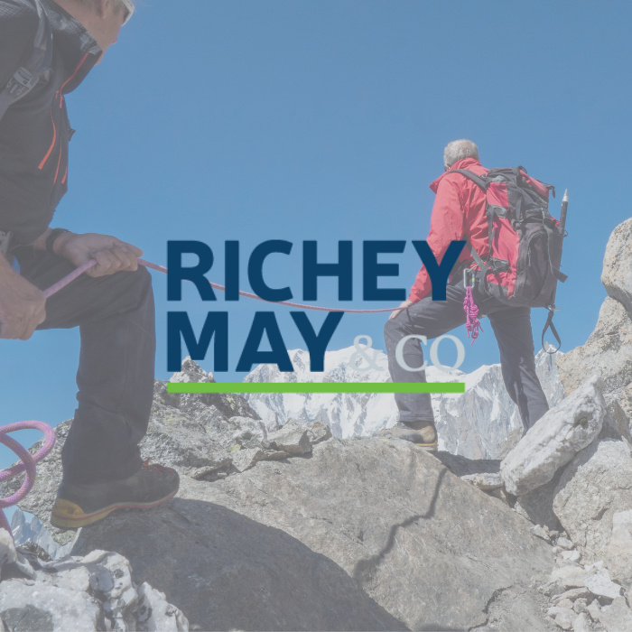 Richey May & Co title with background of two men hiking up a rocky mountain